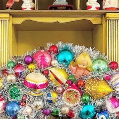 a pile of christmas ornaments sitting on top of a table next to a yellow fireplace