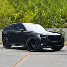 a black suv parked in front of some trees