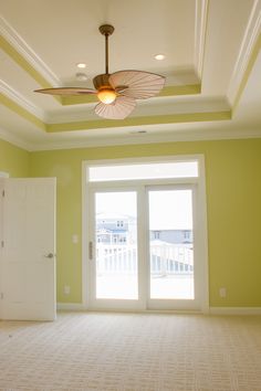 an empty room with a ceiling fan and sliding glass doors