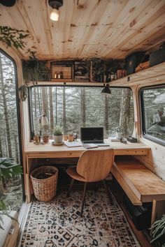 the interior of a camper with a desk, chair and laptop on top of it