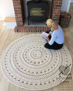 a woman sitting on the floor reading a book in front of an open fire place