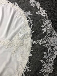 an image of white lace on black and gray fabric with flowers in the center, closeup