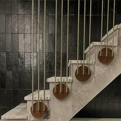 a set of stairs with metal railings and marble handrails in front of a black tiled wall