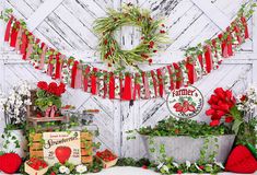 an arrangement of flowers and plants on display in front of a white wall with red ribbon