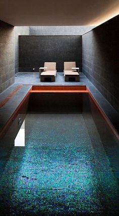 an indoor swimming pool with two lounge chairs