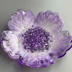 a purple flower shaped bowl sitting on top of a white countertop next to a gray wall