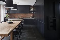 a large wooden table sitting in the middle of a kitchen next to a wall mounted oven