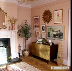 a living room with pink walls and pictures on the wall next to a fire place