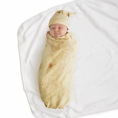 a baby wrapped in a blanket on top of a white sheet