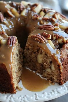 a cake with pecans and caramel drizzled on top is sitting on a plate