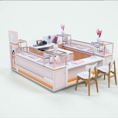 a pink and white model of a restaurant with two tables, chairs and an oven