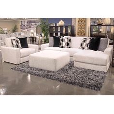 a living room filled with lots of furniture and pillows on top of a gray rug