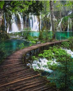 a wooden walkway leads to a waterfall in plitunka national park, croatia