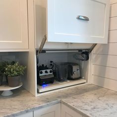 a kitchen with white cabinets and appliances in the cupboards that are open to reveal an appliance