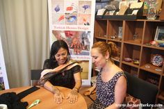 two women sitting at a table in front of a book