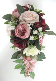 a bridal bouquet with pink and white flowers on the bottom, greenery around it