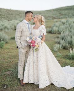 a bride and groom are standing in the grass