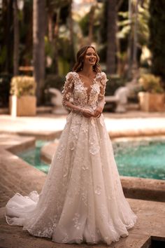 a woman standing in front of a pool wearing a wedding dress