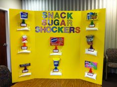 a display with snacks on it in front of a yellow backdrop that says snack sugar shockers