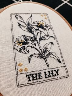 a close up of a embroidery on a piece of cloth with the words, the lily