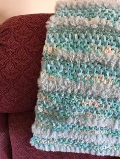 a crocheted blanket sitting on top of a red couch next to a pillow