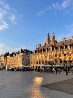 a large building with many windows and people walking around it in the middle of town