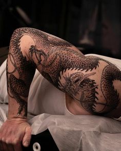 a man with tattoos on his arm laying in bed