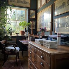 a room filled with lots of plants and pictures hanging on the wall next to a dresser