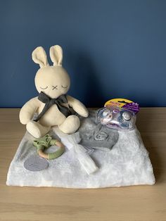 a stuffed rabbit sitting on top of a blanket next to other items and toys in front of a blue wall