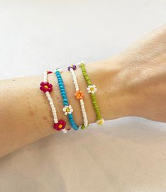 a woman's arm with four bracelets on it, each decorated with different colored beads