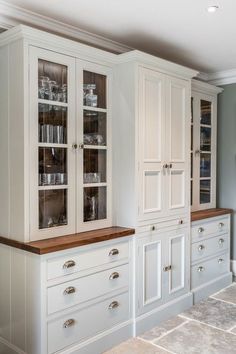 an empty kitchen with white cabinets and glass doors on the front, and brown counter tops