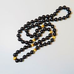 On offer is this beautiful Vintage 14kt. Yellow Gold Black Onyx Gemstone Necklace featuring large 10 mm Onyx Gems with large solid 14 karat yellow gold corrugated spacer beads. It measures a nice long 32 Inches in length with no clasp so it slips easily over your head. The lustrous and highly polished Onyx gems glow like glass and contrast nicely against the shiny 14 karat yellow gold beads. The necklace is hand knotted with black silk cord.  The 14kt yellow gold spacer beads measure a nice larg Luxury Black Pearl Necklace With Round Beads, Formal Onyx Round Bead Necklaces, Black Onyx 8mm Bead Jewelry, Black Onyx Jewelry With 8mm Beads, Black Onyx 8mm Beads Jewelry, Formal Onyx Necklace With Round Beads, Elegant Black Beaded Long Necklace, Formal Onyx Necklace, Luxury Hand-strung Beaded Necklace With Round Beads