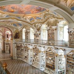 an ornate library with many bookshelves and paintings on the walls