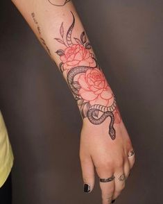 a woman's hand with a snake and roses tattoo on it