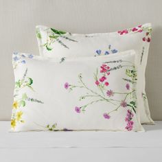 two white pillows with colorful flowers on them