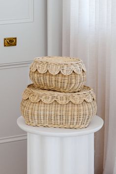 two wicker baskets stacked on top of each other in front of a white door