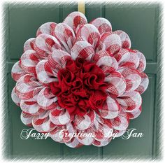 a red and white mesh wreath hanging on a door