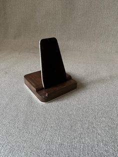 a cell phone sitting on top of a wooden stand in front of a white wall