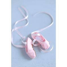 two pink ballet shoes are tied to a white ribbon on a light blue tablecloth