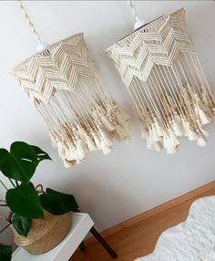 two macrame dream catchers hanging on the wall next to a potted plant