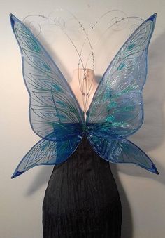 a woman's head is adorned with a blue butterfly wings, which are attached to the back of her head