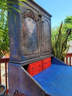 an old wooden cabinet is painted blue and red with a woman's face on it