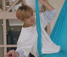 a young man sitting in a blue hammock with his hands on the back