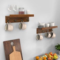 there are cups and spoons hanging from the hooks on the wall above the kitchen counter