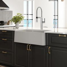 a kitchen with black cabinets and white counter tops, an island style sink and gold handles