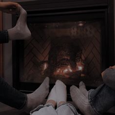 two people sitting in front of a fire place with their feet on the fireplace's mantle