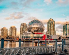 a large metal object sitting in the middle of a body of water next to tall buildings