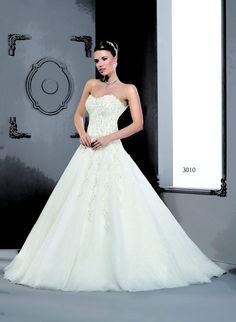 a woman in a white wedding dress standing next to a wall with an open door