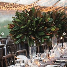 a table set up with place settings and flowers in a vase on the centerpiece