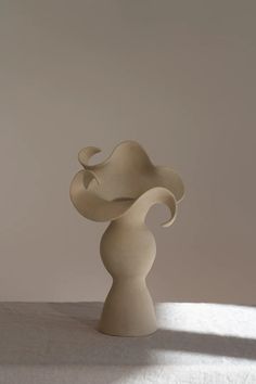 a white sculpture sitting on top of a table next to a wall and window sill